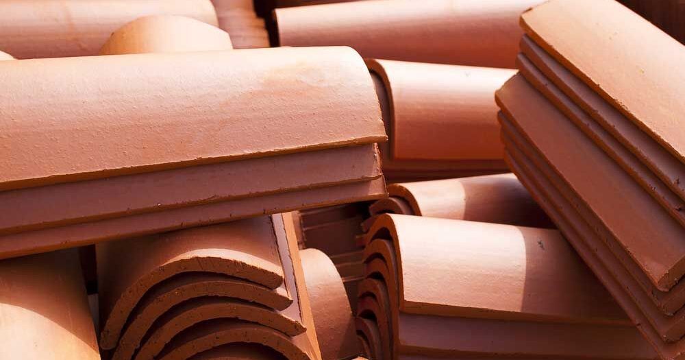 Curved terracotta ridge caps stacked for roofing in Gosford